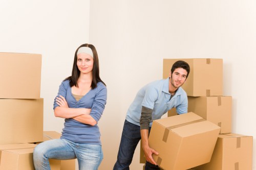 House movers carrying boxes through a Brixton flat with narrow stair access